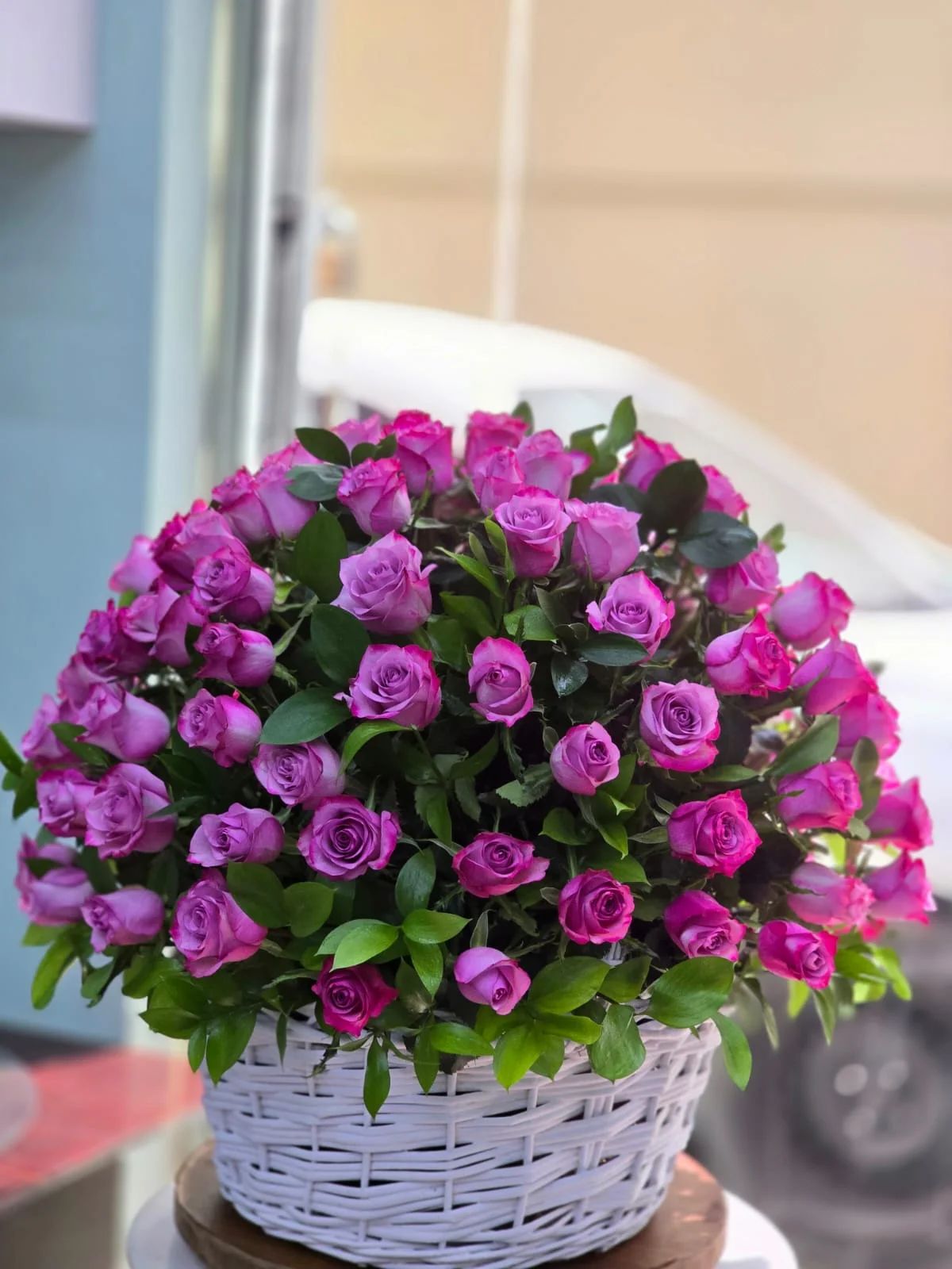 An elegant basket of rich purple roses with natural greenery.