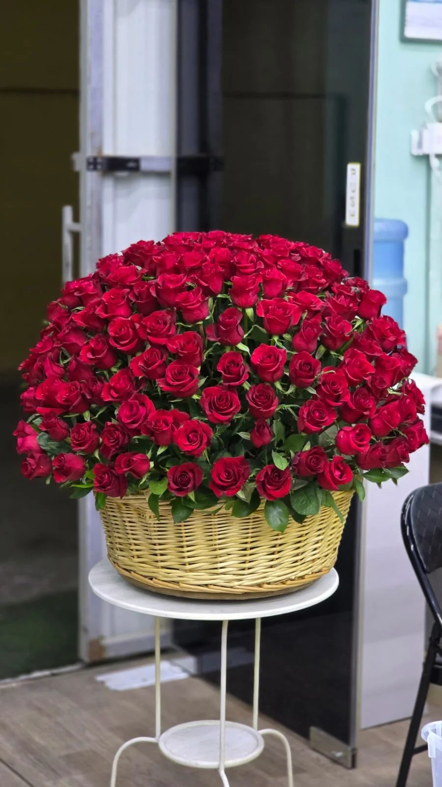 A sophisticated dome of deep red roses arranged in a classic woven basket.