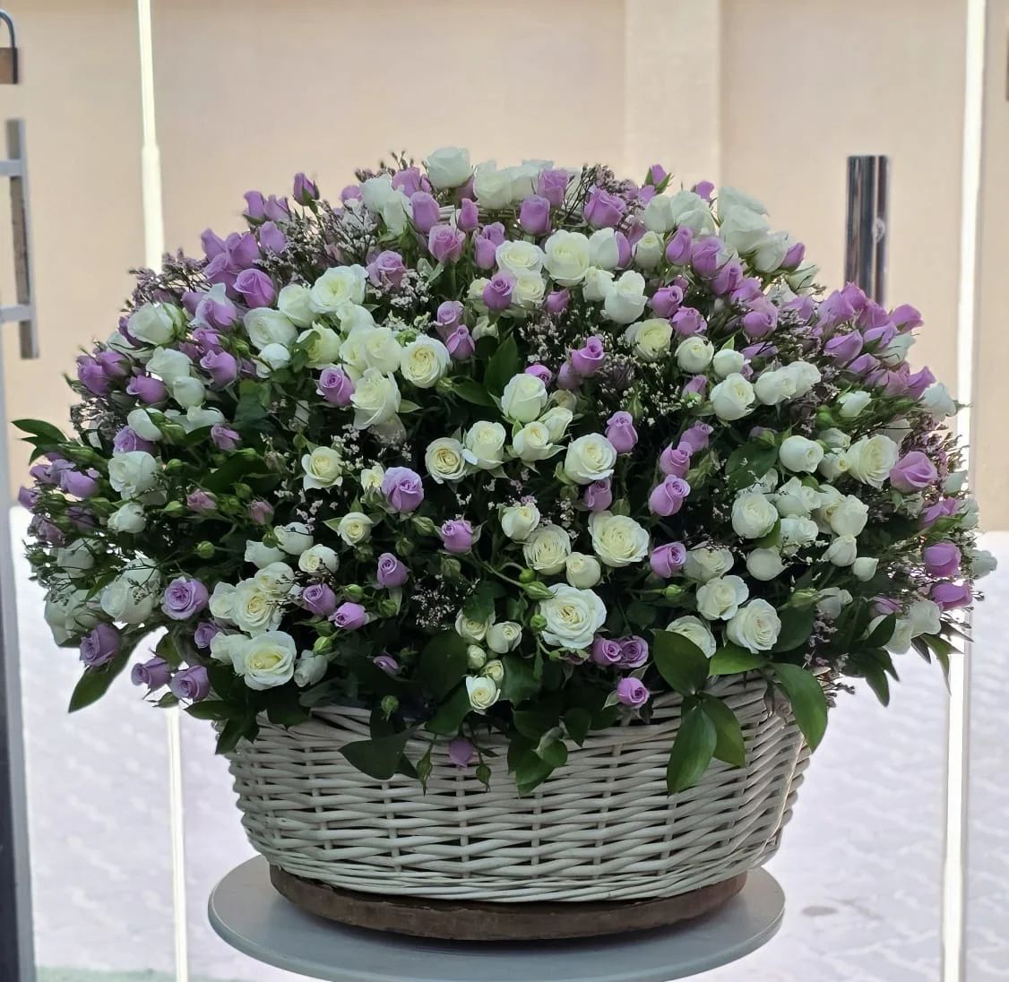 A sophisticated mix of lavender-pink and white spray roses with natural greenery.