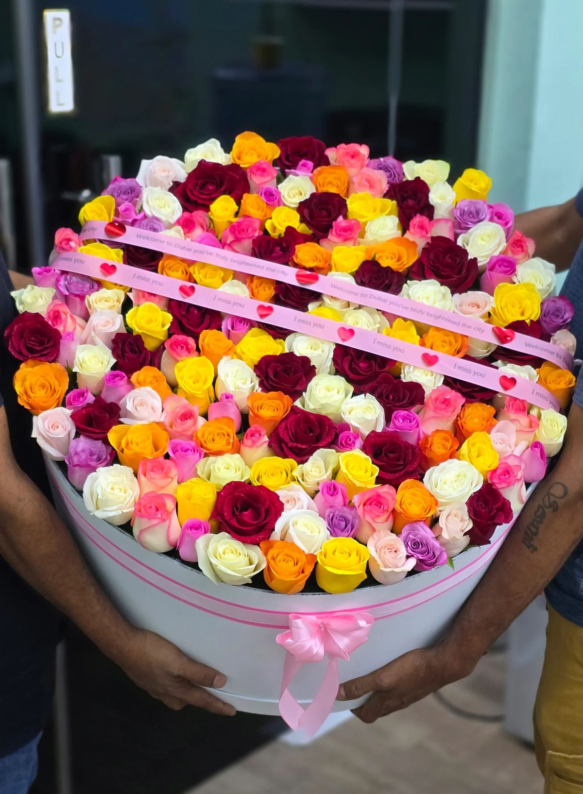 A vibrant luxury box filled with roses in multiple bright colors.