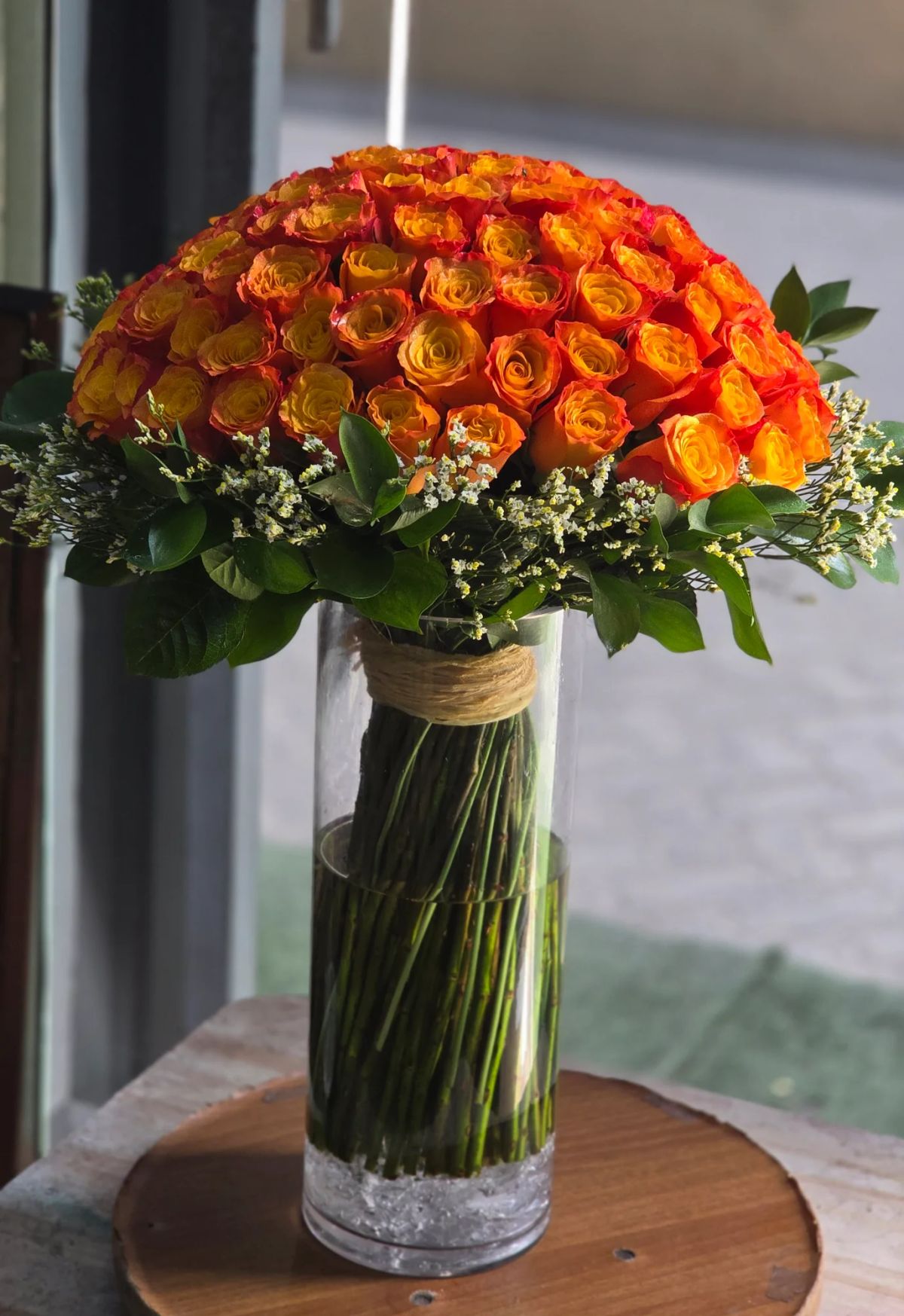 A vibrant arrangement of fresh orange roses elegantly displayed in a clear glass vase.